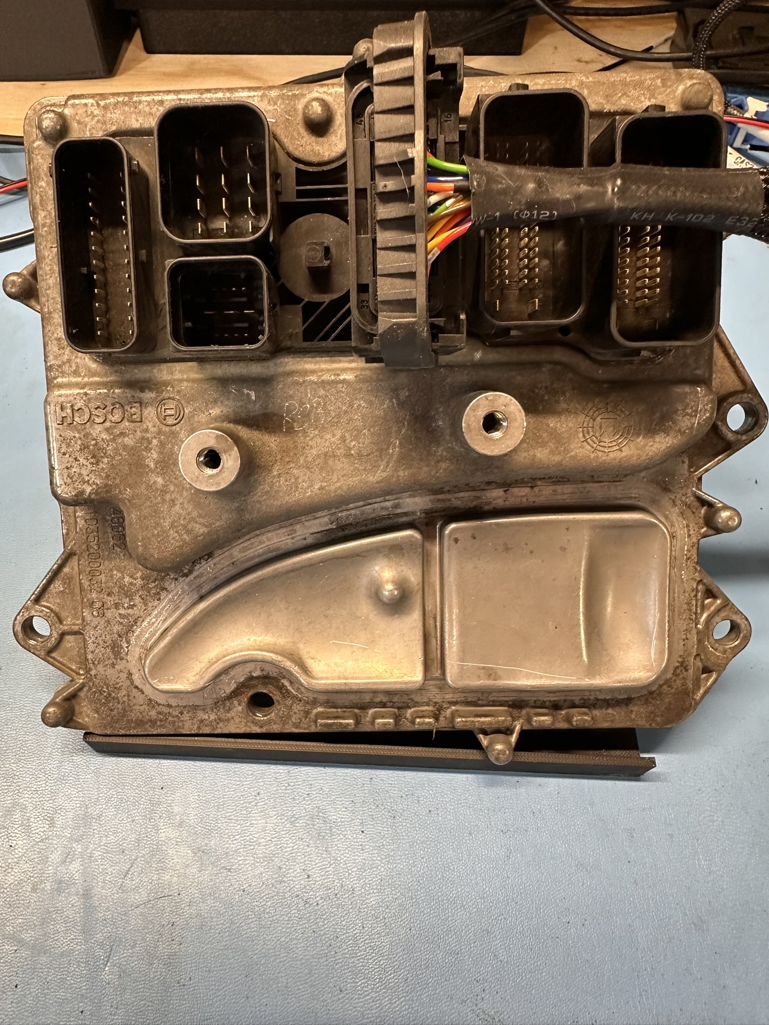 Automotive electronic control module with connector pins and wiring harness on a repair bench